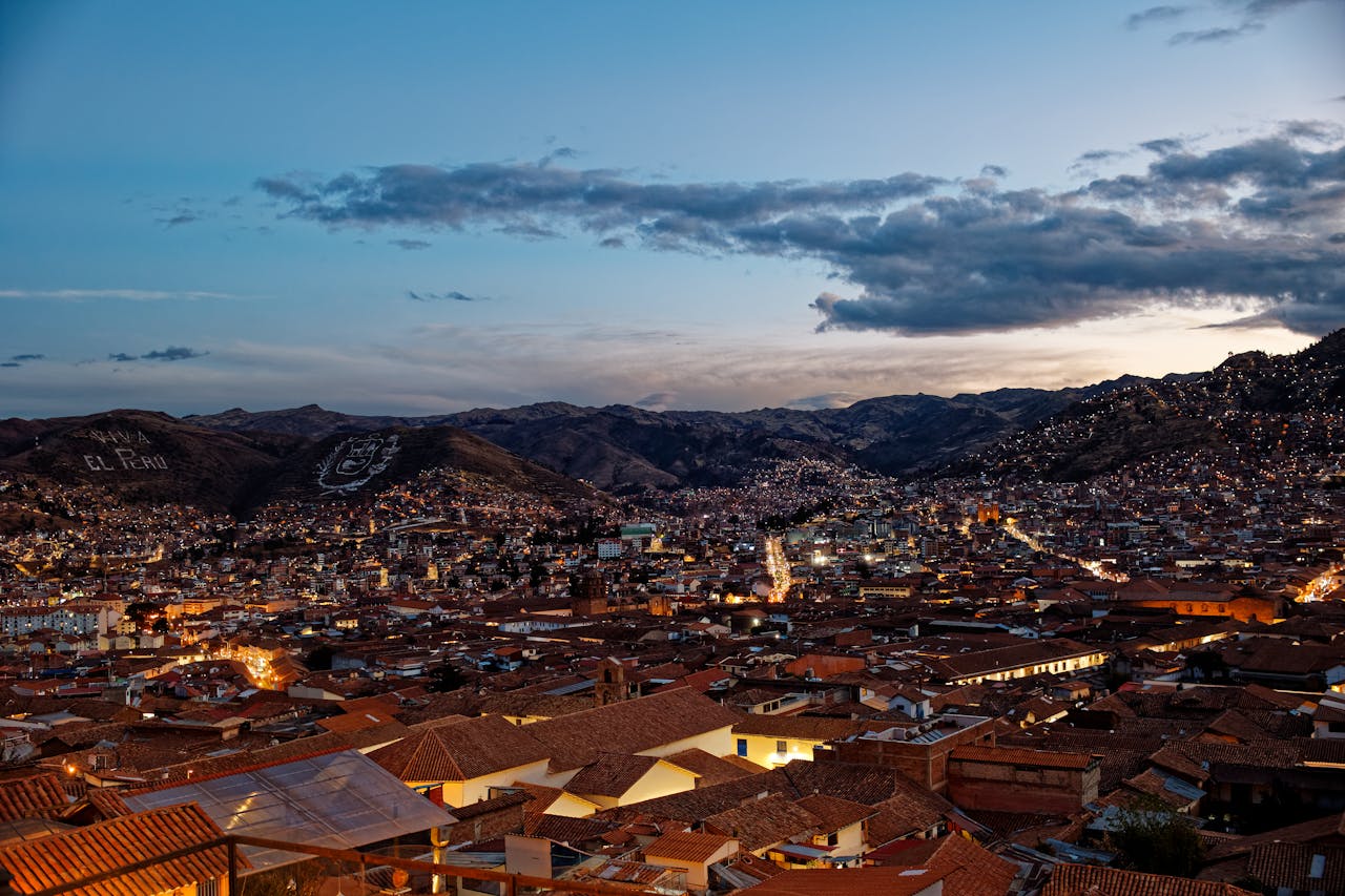 A scenic twilight view of the historical city of Cusco with mountains in the backdrop.